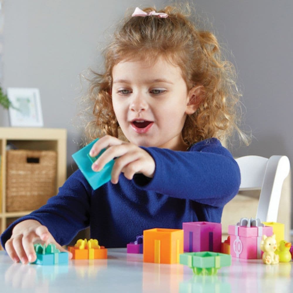 Counting Surprise Party,The Counting Surprise Party is a delightful learning toy designed to provide hours of educational fun for your child. This collection includes a range of numbered boxes, each containing a different colourful object. The boxes are adorned with numerals on the front and a dot array inside the lid, making it easy for children to match the lid to the correct numbered box. Each box is a treasure trove of fun, containing various objects from a friendly cat to a vibrant purple teapot. These