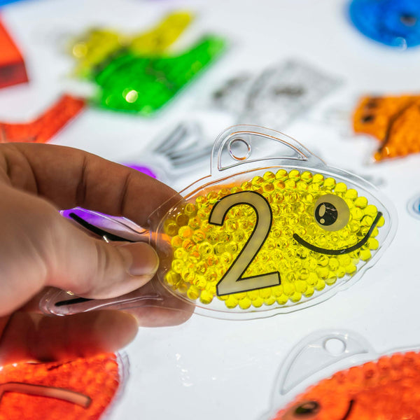 Rainbow Gel Number Fish,Vibrantly rainbow coloured Rainbow Gel Number Fish with numbers 0-20 on one side and their corresponding dots on the other. The Rainbow Gel Number Fish are Ideal for learning to count, to associate numbers with quantities, for colour recognition and for sensory play. The tactile squashy Rainbow Gel Number Fish contain gel-like beads in 7 crystal clear rainbow colours, with a loop at the top for hanging on a string or with pegs. The translucent colours contained within the Rainbow Gel